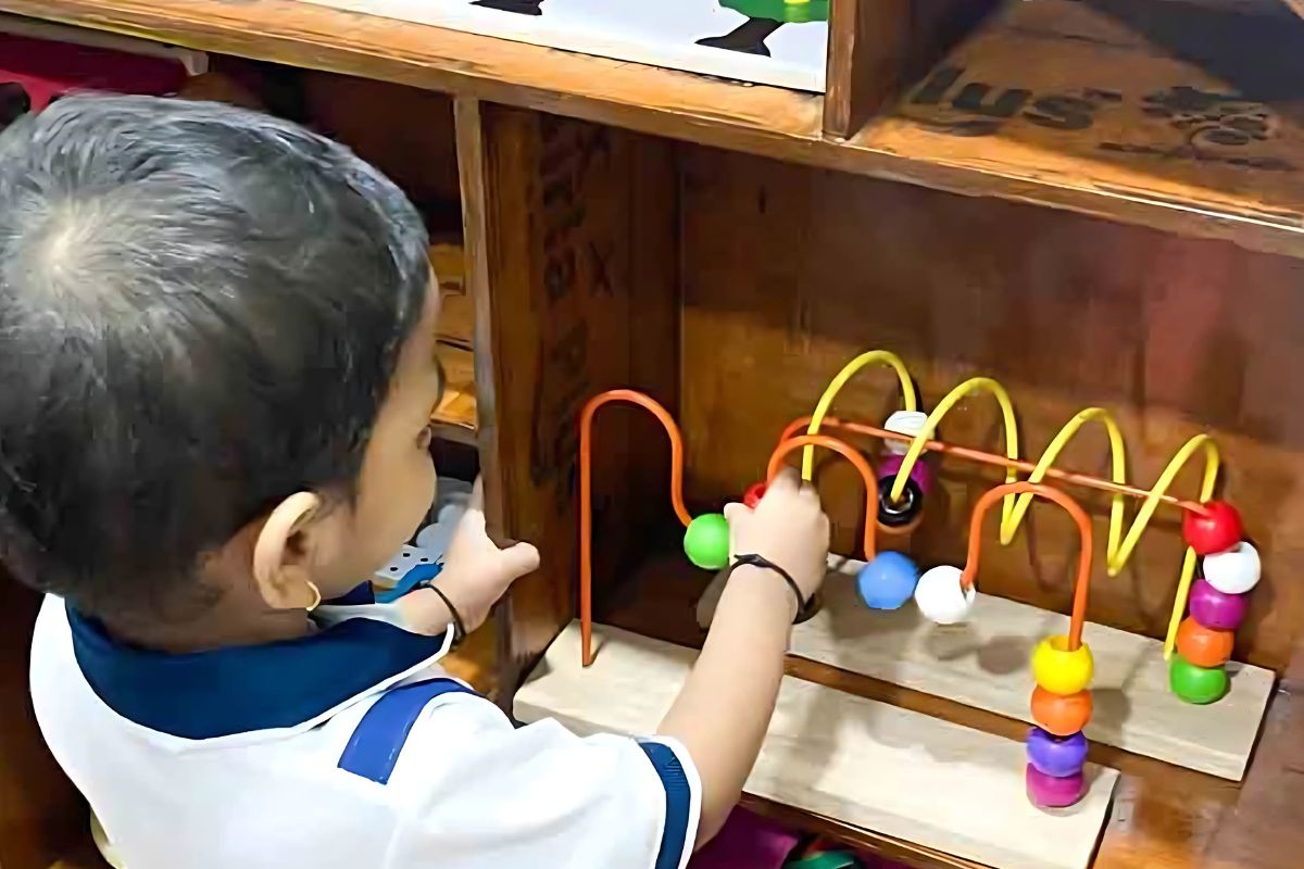 Preschooler at the best preschool in Goregaon engaging in hands on learning with a bead maze