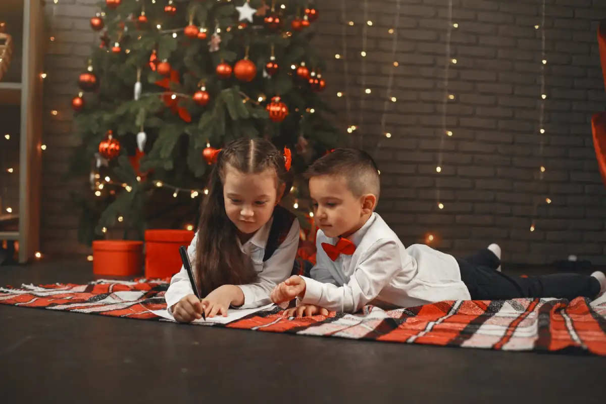 Toddlers decorating a small Christmas tree with colourful ornaments and handmade crafts